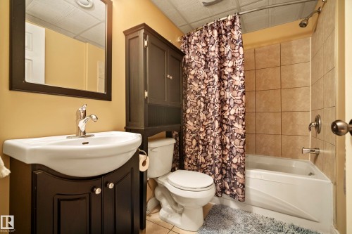 Bathroom featuring a dark wood-finish vanity with an integrated sink and chrome faucet, framed mirror, built-in storage cabinet, and a tiled shower/tub combination - 416 Sparling Crest Sw, Edmonton, AB - Indoor Photo Showing Bathroom