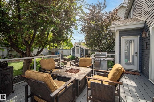 Spacious outdoor deck featuring composite decking, white railing, and a stone-clad fire pit - 416 Sparling Crest Sw, Edmonton, AB - Outdoor With Deck Patio Veranda