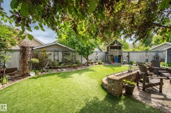 Expansive backyard featuring a lush green lawn and mature perimeter landscaping - 