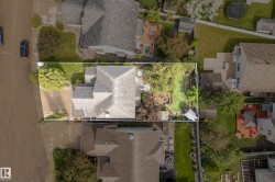 Aerial perspective showcasing a property with a distinct roofline, a paved driveway, and a verdant lawn - 