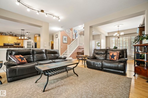 Spacious living area featuring track lighting, a neutral-toned carpet, and light wood-finish flooring - 416 Sparling Crest Sw, Edmonton, AB - Indoor Photo Showing Living Room