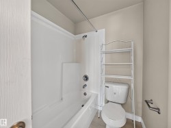 Bathroom featuring a white tub and shower surround, chrome fixtures, and neutral wall tones - 