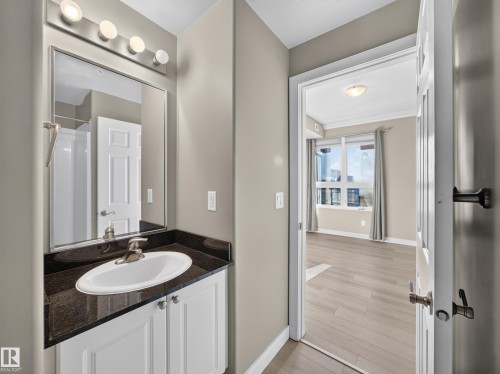 Bathroom vanity with a dark countertop and white cabinetry - #1208 9939 109 St Nw, Edmonton, AB - Indoor Photo Showing Bathroom