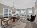 Open-concept living space featuring wood-finish flooring, multiple large windows, and a dining area with a pendant light fixture - #1208 9939 109 St Nw, Edmonton, AB  - Indoor 