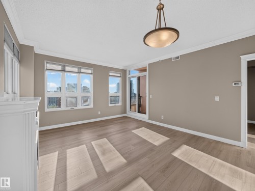 Spacious room with wood-finish flooring, crown molding, and a built-in fireplace mantel - #1208 9939 109 St Nw, Edmonton, AB - Indoor Photo Showing Other Room