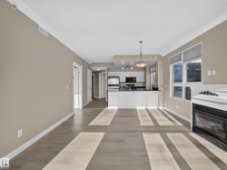 Open-concept living area featuring light wood-finish flooring and a built-in fireplace - 