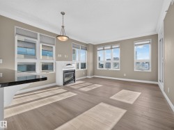 Spacious living area featuring light wood-finish flooring, a white mantel fireplace, and a black countertop bar - 