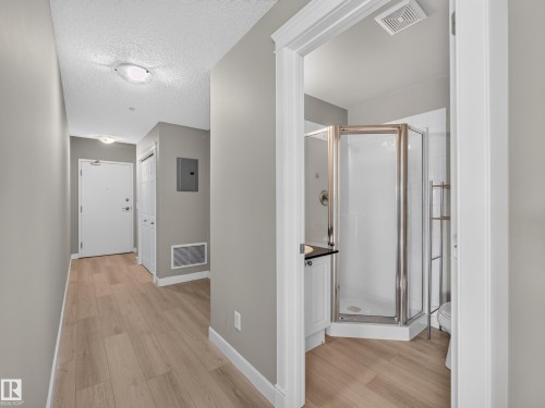 Entryway featuring wood-finish flooring, light grey wall paint, and a built-in storage closet - #1208 9939 109 St Nw, Edmonton, AB - Indoor Photo Showing Other Room
