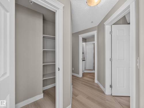 Hallway featuring wood-finish flooring, neutral wall paint, and white trim - #1208 9939 109 St Nw, Edmonton, AB - Indoor Photo Showing Other Room
