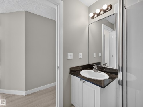Bathroom vanity featuring a dark countertop, an undermount sink with a chrome faucet, and white cabinetry - #1208 9939 109 St Nw, Edmonton, AB - Indoor Photo Showing Bathroom