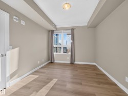 Spacious room featuring wood-finish flooring, neutral-toned walls, a large window, and white trim - 