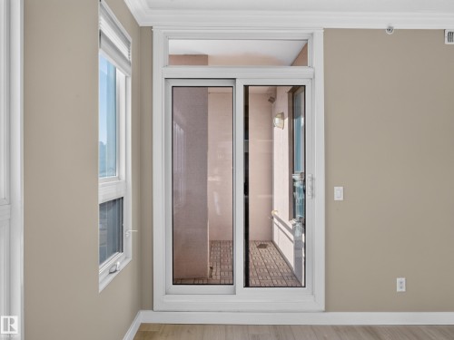 Glass sliding door providing access to an exterior space with brick-patterned flooring - #1208 9939 109 St Nw, Edmonton, AB - Indoor Photo Showing Other Room