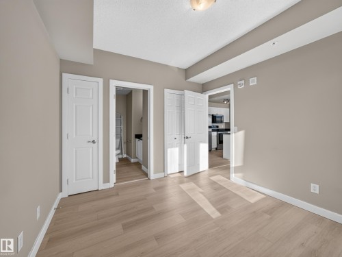 Contemporary room featuring light wood-finish flooring, neutral-toned walls, white baseboards, and multiple doorways - #1208 9939 109 St Nw, Edmonton, AB - Indoor Photo Showing Other Room