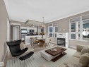 Open-concept living space featuring wood-finish flooring, a contemporary fireplace with a white mantel, and multiple windows - #1208 9939 109 St Nw, Edmonton, AB  - Indoor Photo Showing Living Room With Fireplace 