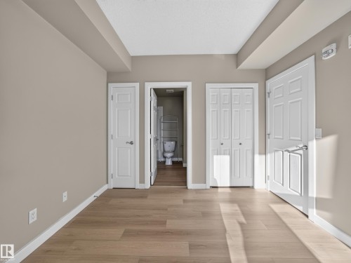 Spacious room featuring wood-finish flooring, neutral-toned walls, and white trim - #1208 9939 109 St Nw, Edmonton, AB - Indoor Photo Showing Other Room
