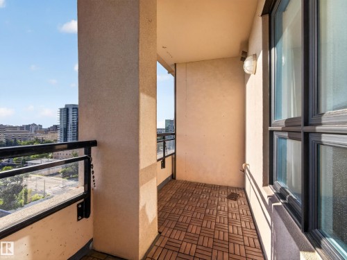Outdoor balcony featuring wood-finish flooring, a wall-mounted light fixture, and black-framed windows - #1208 9939 109 St Nw, Edmonton, AB - Outdoor With Balcony With Exterior