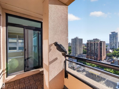 Private balcony featuring wood-finish tile flooring and a glass railing with a black metal frame - #1208 9939 109 St Nw, Edmonton, AB - Outdoor With Balcony