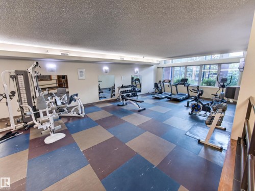 Dedicated fitness space featuring a multi-station weight machine, treadmills, stationary bikes, and an elliptical trainer - #1208 9939 109 St Nw, Edmonton, AB - Indoor Photo Showing Gym Room