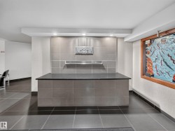 Entryway featuring a reception desk with a dark countertop, grey tile facade, and overhead recessed lighting - 