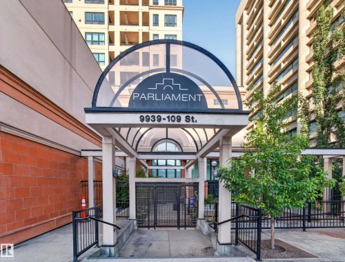 Building entrance featuring a glass-covered archway, "Parliament" signage, and street address - #1208 9939 109 St Nw, Edmonton, AB - Outdoor With Balcony