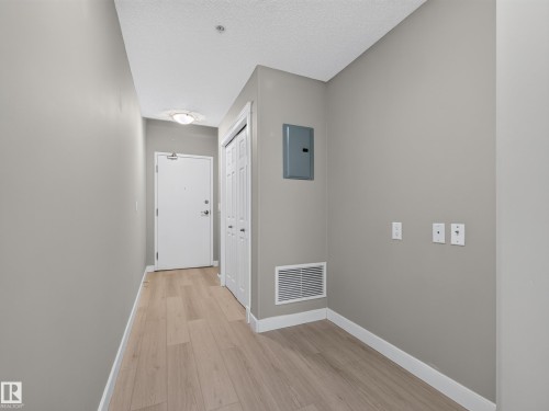 Entryway featuring light wood-finish flooring, neutral gray walls, a white entry door, a flush-mount ceiling light, and a bi-fold closet door - #1208 9939 109 St Nw, Edmonton, AB - Indoor Photo Showing Other Room