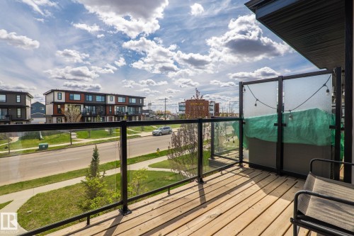 Outdoor balcony featuring wood-finish decking, black metal railings with glass panels, and a partial privacy screen - 8282 Chappelle Way Sw, Edmonton, AB - Outdoor