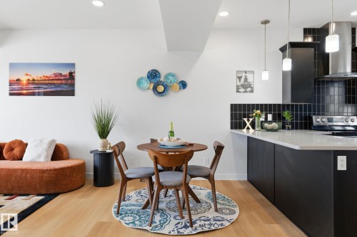 Open-concept living space featuring wood-finish flooring, recessed lighting, and a modern kitchen with dark cabinetry, light countertops, and a subway tile backsplash - 8282 Chappelle Way Sw, Edmonton, AB - Indoor Photo Showing Dining Room