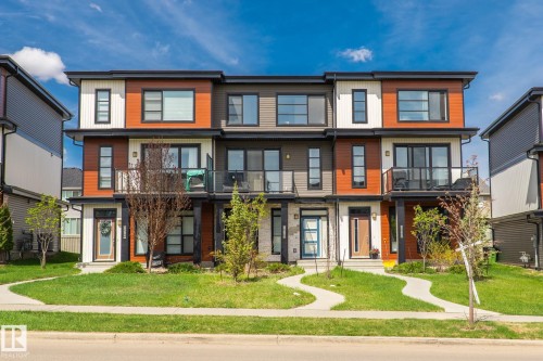 Contemporary multi-story townhomes featuring contrasting horizontal siding in white, wood-tone, and charcoal - 8282 Chappelle Way Sw, Edmonton, AB - Outdoor With Facade