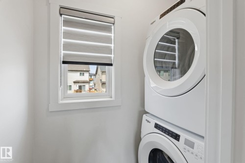 Dedicated laundry area featuring a white stacked washer and dryer unit - 8282 Chappelle Way Sw, Edmonton, AB - Indoor Photo Showing Laundry Room