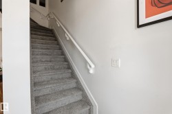 Carpeted staircase with light gray pile and white handrails - 