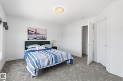 Spacious bedroom featuring plush gray carpeting, crisp white walls, and a contemporary flush-mount ceiling light - 