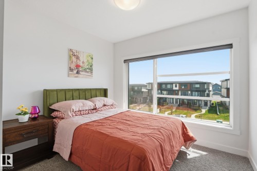 Spacious room featuring a large window, neutral wall paint, and carpeted flooring - 8282 Chappelle Way Sw, Edmonton, AB - Indoor Photo Showing Bedroom