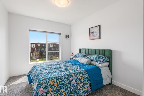 Bright bedroom featuring a large window, plush carpeting, and a flush-mount ceiling light - 8282 Chappelle Way Sw, Edmonton, AB - Indoor Photo Showing Bedroom