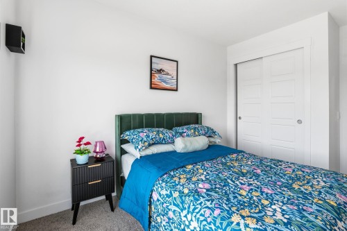 Bedroom featuring a paneled sliding closet door, white walls, and a green velvet headboard - 8282 Chappelle Way Sw, Edmonton, AB - Indoor Photo Showing Bedroom