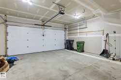 Spacious garage featuring a concrete floor, overhead lighting, and an automatic garage door opener - 