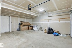 Spacious garage with concrete flooring, overhead lighting, and an overhead garage door mechanism - 