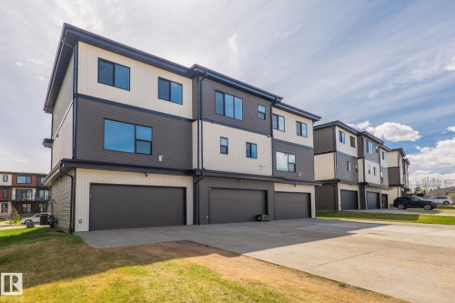Modern multi-level townhome featuring a neutral-toned exterior with dark trim, multiple windows, and an integrated garage - 8282 Chappelle Way Sw, Edmonton, AB - Outdoor