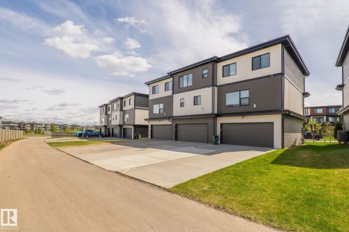 Contemporary townhome exterior featuring multi-toned siding, black-framed windows, and a built-in garage with a dark door - 8282 Chappelle Way Sw, Edmonton, AB - Outdoor