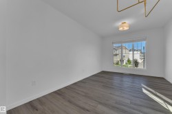 Bright room featuring wood-finish flooring, a large window with roller shades, and a flush mount ceiling fixture - 