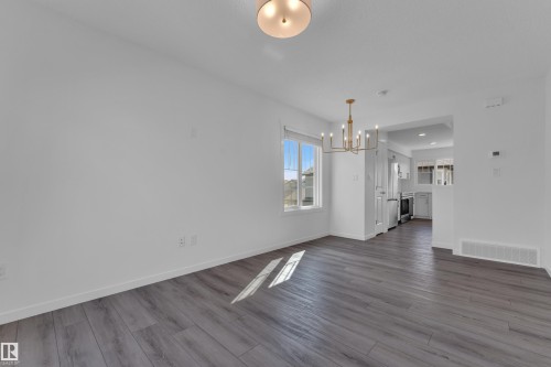 Open-concept living area featuring wood-finish flooring, a modern brass chandelier, and recessed lighting - #64 17832 78 St Nw Nw, Edmonton, AB - Indoor Photo Showing Other Room