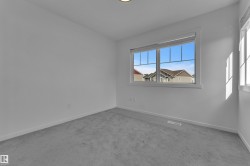 Room featuring light gray carpeting, white walls, and a large window with white trim - 