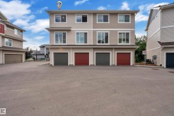 Multi-level exterior featuring light-toned siding, multiple windows, and two distinct garage doors - 
