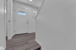 Entryway featuring wood-finish flooring, a white paneled door with an upper window, and a white transom window - 