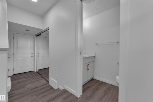 Wood-finish flooring throughout, featuring a mirrored closet, two white panel doors, and a bathroom with a modern vanity and toilet - #64 17832 78 St Nw Nw, Edmonton, AB - Indoor