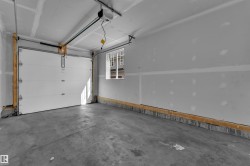 Spacious garage featuring a concrete floor, white panel garage door, automatic opener, and a single window - 