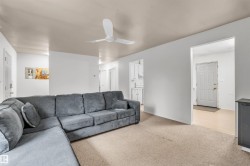Carpeted living area featuring a ceiling fan and white painted walls - 