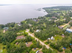 Expansive aerial landscape featuring a large body of water, extensive tree coverage, and multiple residential properties - 