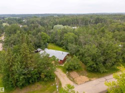 Detached residence with a gray shingle roof, surrounded by mature trees and natural landscaping - 