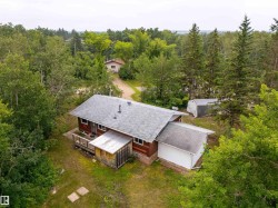 Aerial perspective of a property featuring a single-story residence with a gray shingled roof and wood siding - 