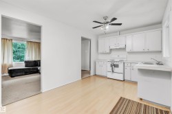 Bright kitchen featuring white cabinetry, a white electric range, and a single basin sink - 